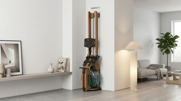 Un rameur à eau en bois haut de gamme Wenoker RW211-50, rangé complètement à la verticale contre le mur d'un salon minimaliste