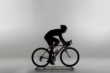 Un cycliste sur une route pittoresque, entouré d'icônes représentant la musculation, la natation et la course, illustrant le concept d'entraînement croisé pour cyclistes.